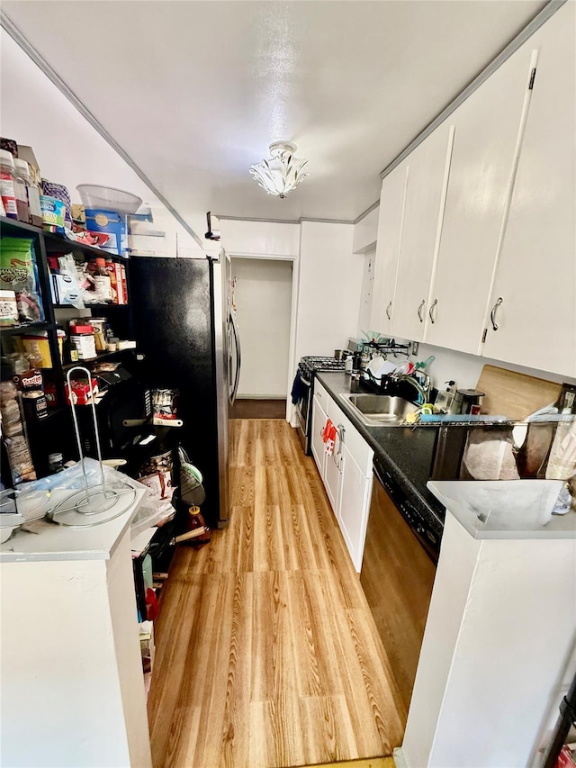 kitchen with appliances with stainless steel finishes, white cabinetry, light hardwood / wood-style flooring, and sink