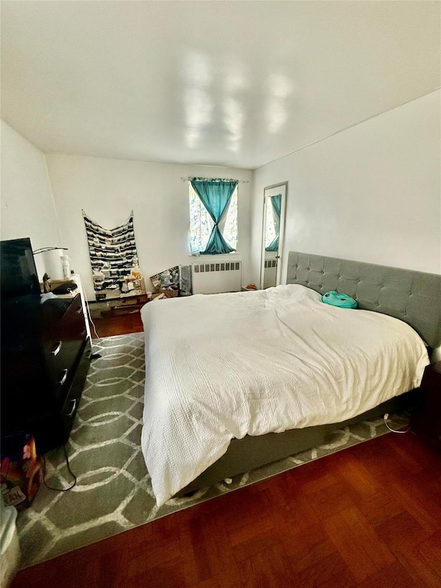 bedroom with radiator heating unit and dark parquet floors