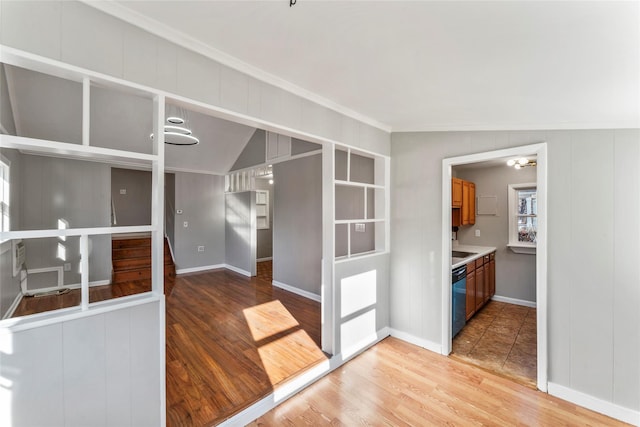 kitchen featuring hardwood / wood-style floors, black dishwasher, vaulted ceiling, and ornamental molding