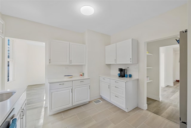 kitchen with dishwasher, light hardwood / wood-style floors, white cabinetry, and sink