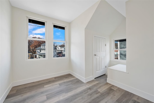 spare room featuring light wood-type flooring and vaulted ceiling