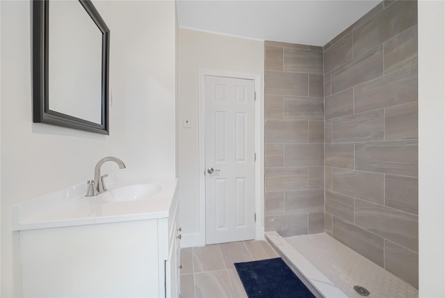 bathroom with tile patterned flooring, vanity, and tiled shower