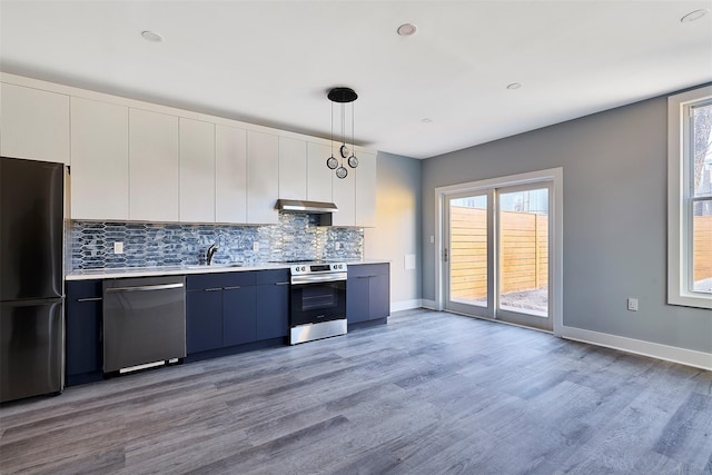 kitchen featuring white cabinets, appliances with stainless steel finishes, decorative light fixtures, and light hardwood / wood-style floors