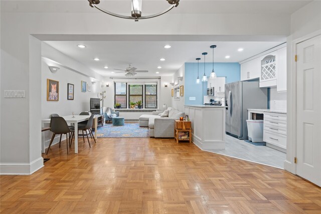 living room featuring ceiling fan with notable chandelier and light parquet flooring