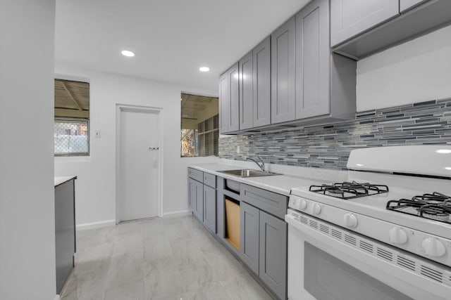 kitchen with gray cabinets, sink, white gas range oven, and tasteful backsplash