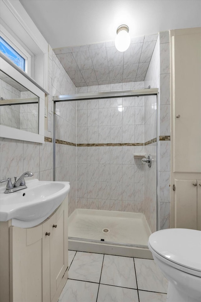 bathroom featuring vanity, a shower with shower door, tile walls, and toilet