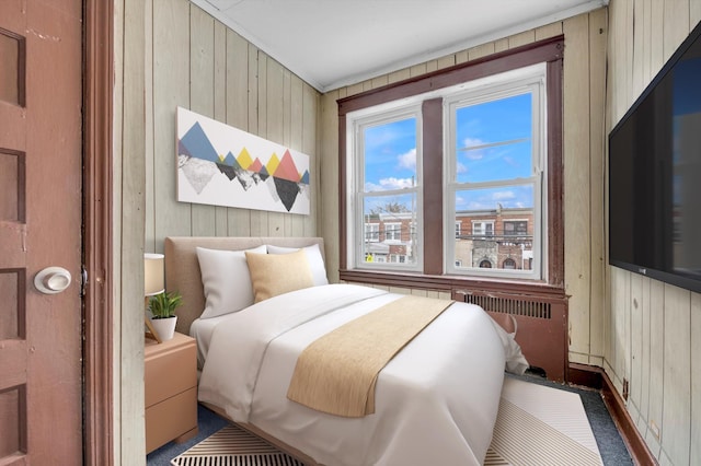 bedroom with wooden walls, radiator, and dark colored carpet