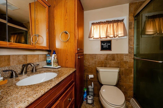 bathroom featuring vanity, toilet, a shower with door, and tile walls