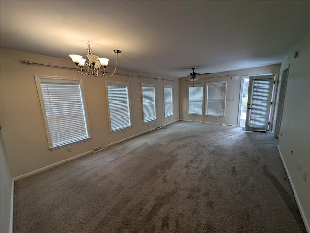 unfurnished living room featuring carpet flooring, a wealth of natural light, and ceiling fan with notable chandelier