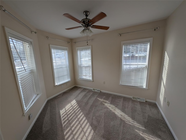 carpeted spare room featuring ceiling fan and a healthy amount of sunlight