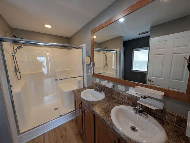 bathroom with hardwood / wood-style floors, vanity, and a shower with shower door