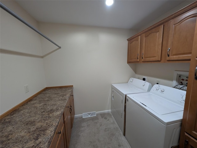 washroom featuring washing machine and dryer, light colored carpet, and cabinets