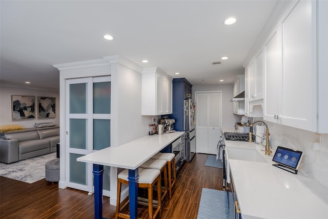 kitchen with a kitchen breakfast bar, stainless steel appliances, dark wood-type flooring, and ventilation hood