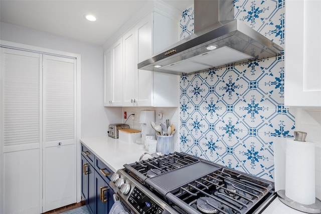 kitchen featuring decorative backsplash, white cabinetry, wall chimney range hood, and gas stove