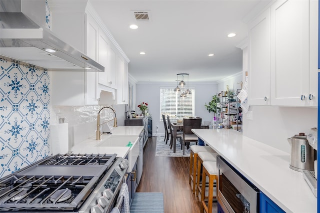 kitchen featuring stainless steel range, dark wood-type flooring, wall chimney range hood, crown molding, and white cabinets