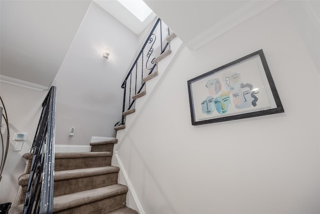 staircase featuring a skylight and crown molding