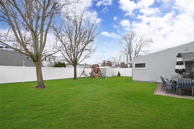 view of yard featuring a patio area, a playground, and a shed