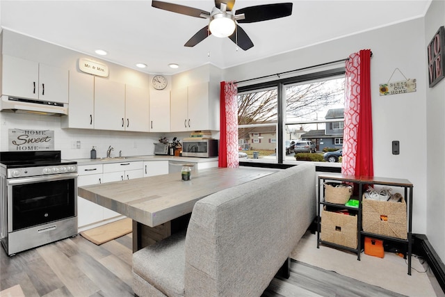 kitchen featuring white cabinets, appliances with stainless steel finishes, light hardwood / wood-style floors, and tasteful backsplash