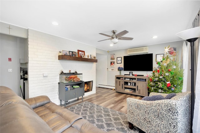 living room featuring light wood-type flooring, a wall unit AC, ceiling fan, a baseboard heating unit, and a fireplace