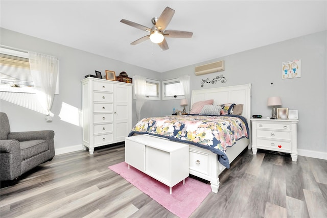 bedroom with ceiling fan, wood-type flooring, and a wall unit AC