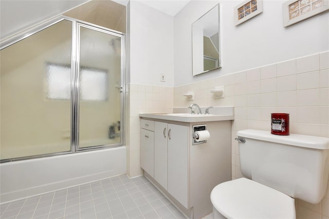 full bathroom featuring tile patterned flooring, toilet, bath / shower combo with glass door, and tile walls