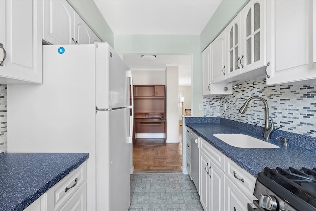 kitchen with white fridge, range with gas cooktop, decorative backsplash, white cabinets, and sink