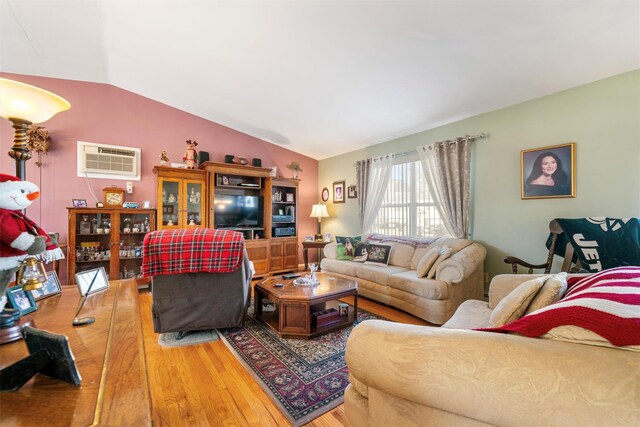 living room featuring hardwood / wood-style floors, lofted ceiling, and a wall unit AC