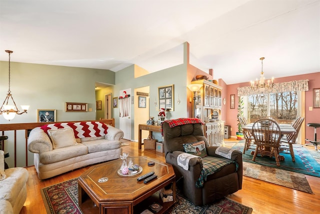 living room with light hardwood / wood-style floors, lofted ceiling, and a notable chandelier