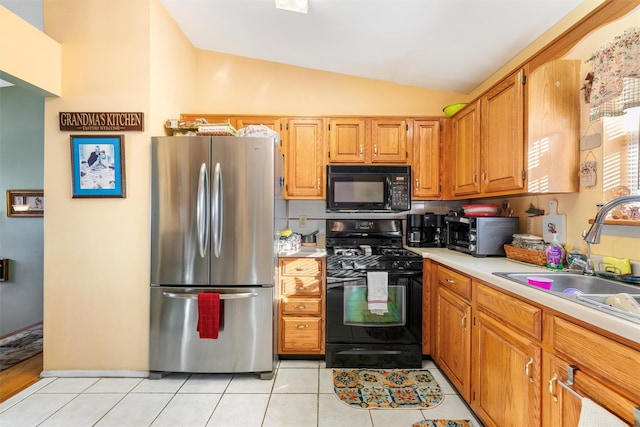 kitchen featuring light tile patterned floors, sink, vaulted ceiling, and black appliances