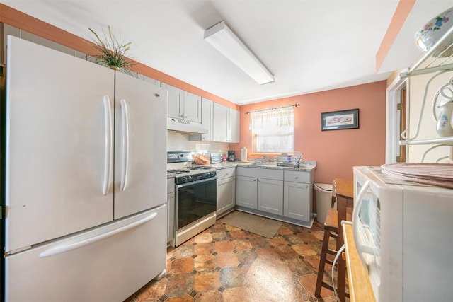 kitchen with gray cabinetry, sink, washing machine and dryer, white refrigerator, and range with gas stovetop