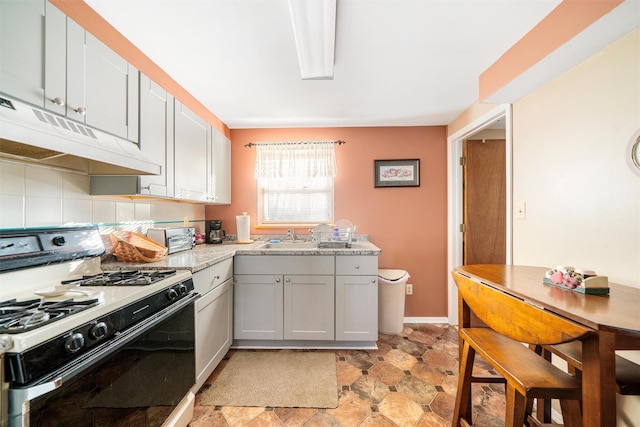 kitchen with white gas range oven, backsplash, and sink