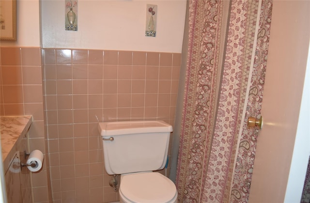 bathroom featuring vanity, toilet, and tile walls