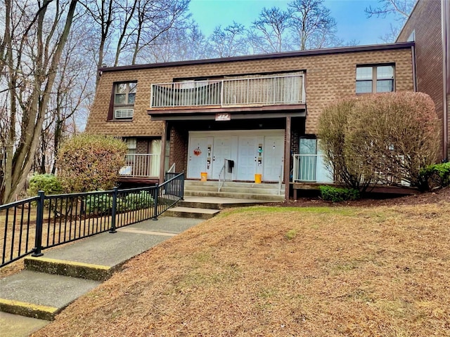 view of front of property featuring a balcony and a front lawn