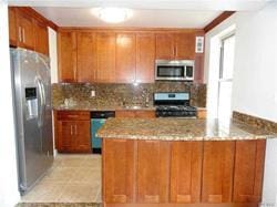 kitchen featuring kitchen peninsula, backsplash, stainless steel appliances, and light stone counters