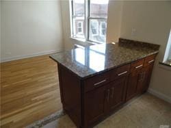 kitchen featuring stone countertops, light hardwood / wood-style floors, dark brown cabinets, and kitchen peninsula