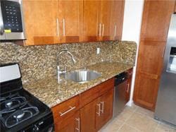 kitchen with light stone counters, sink, light tile patterned flooring, and stainless steel appliances