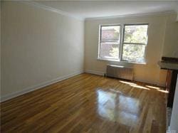 unfurnished living room featuring dark hardwood / wood-style flooring, ornamental molding, and radiator heating unit