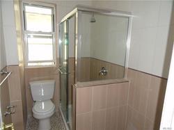 bathroom featuring a shower with door, tile walls, and toilet