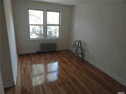 empty room featuring dark hardwood / wood-style floors and radiator