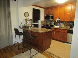 kitchen with a breakfast bar area, kitchen peninsula, stainless steel appliances, and light wood-type flooring