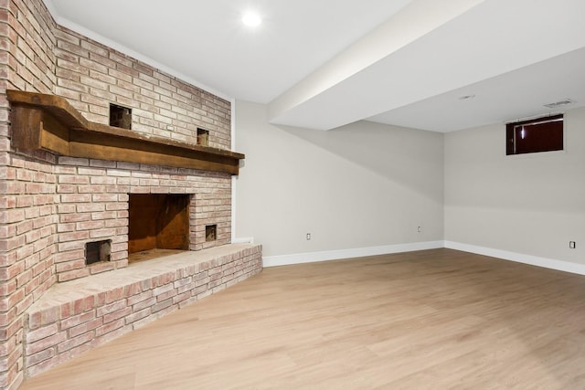 unfurnished living room with a brick fireplace and light hardwood / wood-style flooring