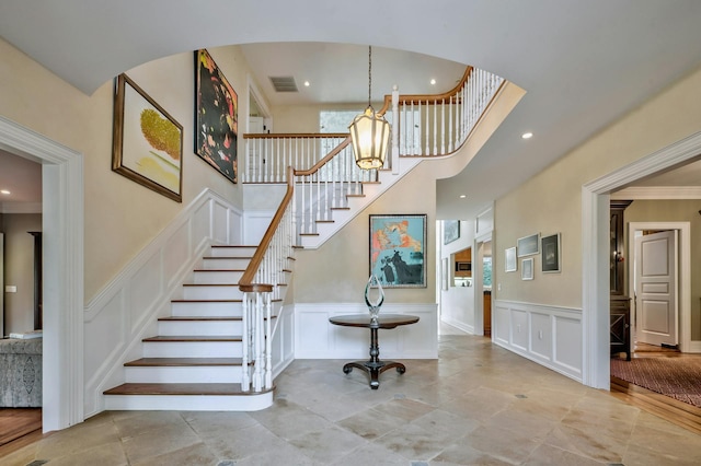 staircase with an inviting chandelier and ornamental molding