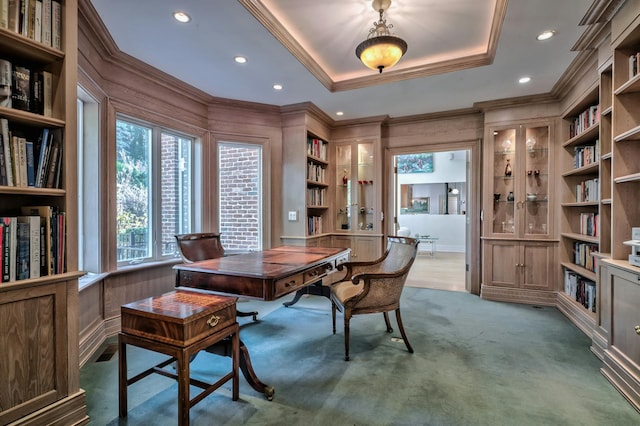 carpeted office with crown molding, a tray ceiling, built in shelves, and wood walls