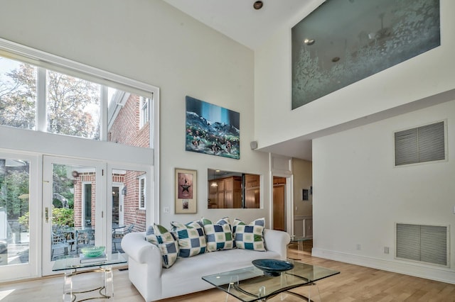 living room with a towering ceiling and light hardwood / wood-style floors