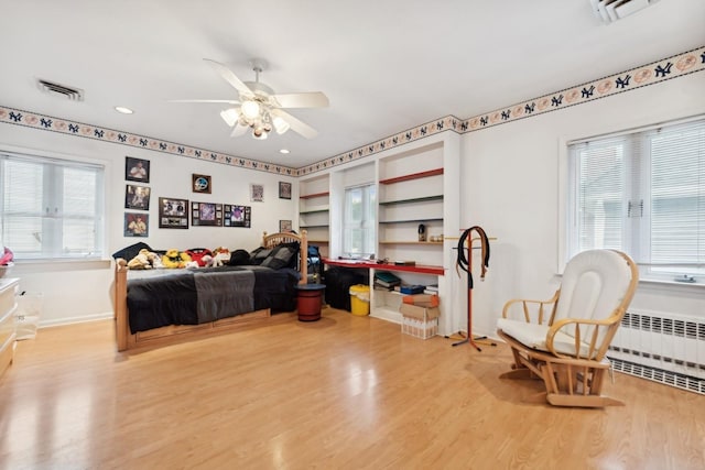 bedroom with ceiling fan, radiator heating unit, and light wood-type flooring