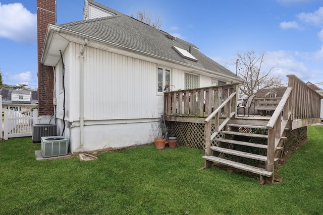 view of side of property with central AC unit, a yard, and a wooden deck