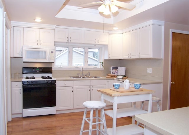 kitchen with white appliances, light hardwood / wood-style flooring, white cabinetry, and sink