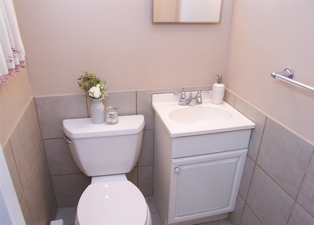 bathroom with vanity, toilet, and tile walls