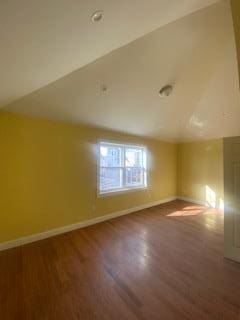 bonus room with hardwood / wood-style floors and vaulted ceiling