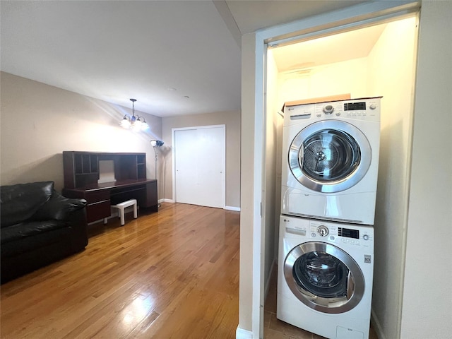 laundry area with a chandelier, hardwood / wood-style floors, and stacked washer / drying machine